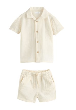 Béžová košeľa s krátkym rukávom na gombíky s golierom a zodpovedajúce šortky so sťahovacou šnúrkou, obe vyrobené z textúrovaného ľahkého materiálu.