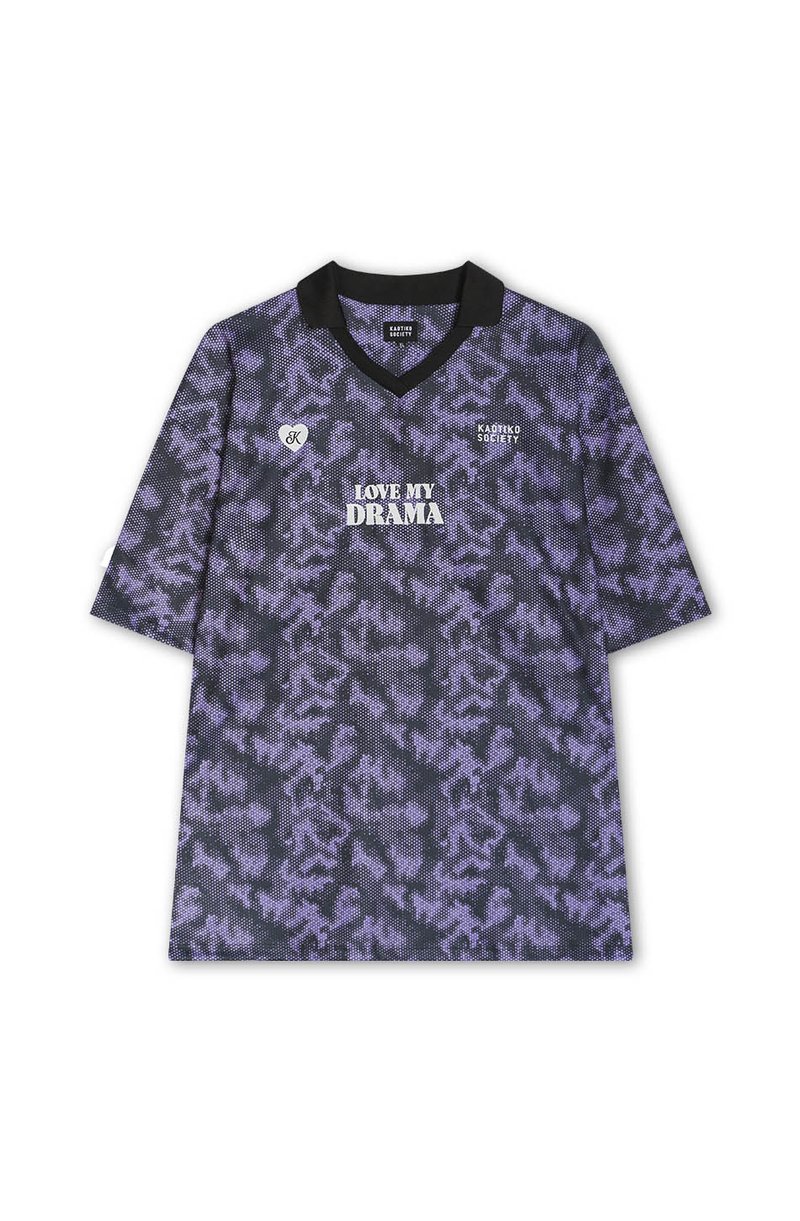 Jersey deportivo de color morado con un cuello en V negro. Presenta el texto "ME ENCANTA MI DRAMA" en blanco, junto con un pequeño logotipo de corazón.