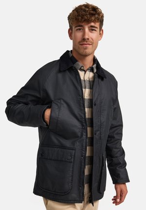 Chaqueta negra, impermeable, con cuello, cierre delantera a presión y dos bolsillos grandes. Textura suave con un diseño clásico.