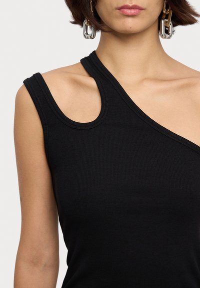 Débardeur noir à côtes avec encolure asymétrique, doté d'une seule bretelle et d'un tissu texturé. Comprend des boucles d'oreilles en anneau métallique.