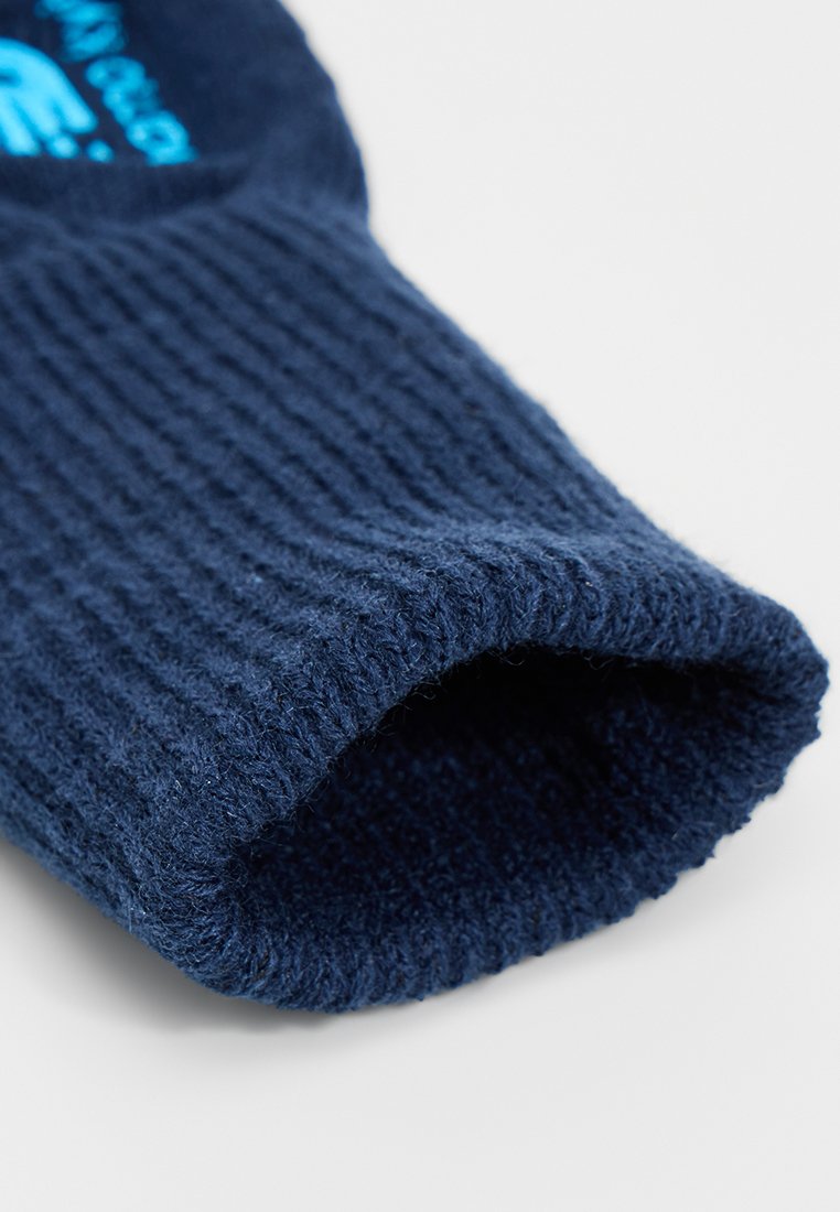 Gant de laine bleu marine avec texture côtelée, présentant un large poignet et un aspect doux. L'intérieur affiche une couleur sombre uniforme.