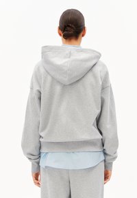 Grauer Kapuzenpullover mit lockerem Schnitt, gerippten Bündchen und weicher Textur, getragen über einem hellblauen Hemd. Die Rückansicht zeigt das Design.