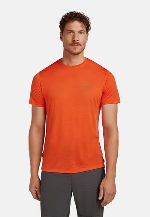 Heldere oranje shirt met korte mouwen, gemaakt van lichte stof met een gestructureerd patroon. Voorzien van een klein logo op de borst en een ronde halslijn.