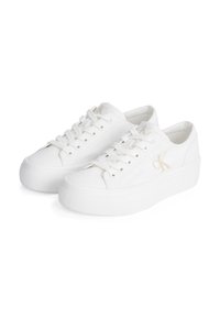 Balti zema profila platformas sporta apavi ar šņorēm un smalku "ck" logotipu sānos, attēloti uz baltas fona.