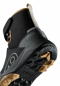 Wodoodporna czarna botka z gumową podeszwą, teksturowanymi akcentami i beżowym wierzchem. Posiada rzep i sznurowadła dla bezpiecznego dopasowania.