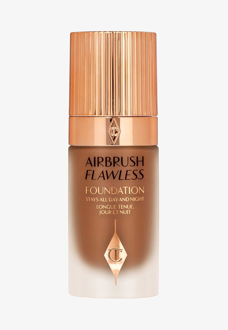 Airbrush Flawless Foundation in a frosted ombre glass bottle. Features a ribbed gold cap and brand logo in an elegant geometric design.