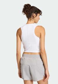 Biele skrátené tielko a svetlosivé šortky. Tielko má okrúhly výstrih a bezrukávový strih; šortky majú zadné vrecko a elastický pás.