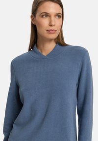 Maglione lavorato a maglia di colore azzurro chiaro con colletto a V e maniche lunghe. Il tessuto appare morbido, con una leggera texture e dettagli minimi.