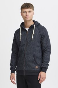 Hooded zip-up sweatshirt in dark gray heather, featuring cream drawstring toggles, front pockets, and a leather logo patch on the lower side.