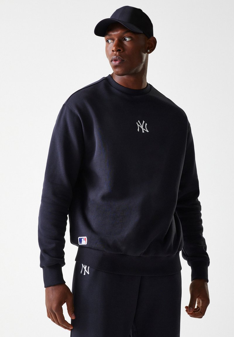 Sudadera azul marino hecha de un material suave, con un logotipo bordado en plata en el pecho y una etiqueta blanca de la MLB en el dobladillo.