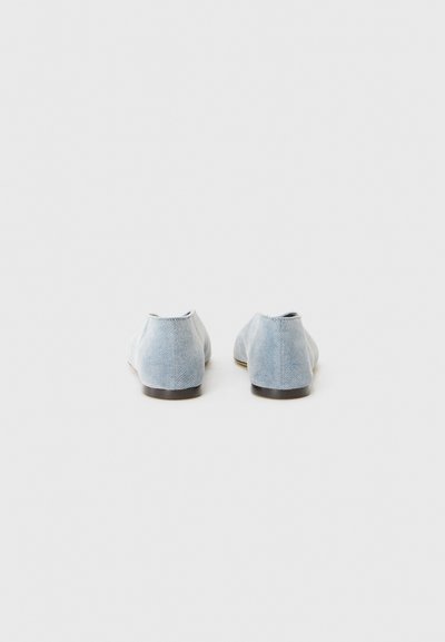 Lysblå denim slip-on sko med lav profil, struktureret overflade og en brun gummisål. Enkelt design uden synlige detaljer.