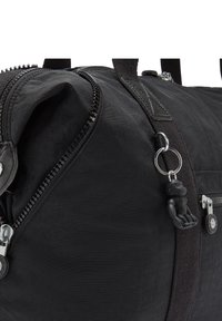 Borsa a duffle nera con superficie texturizzata, dotata di chiusura con più cerniere, manici in tessuto e un piccolo portachiavi a forma di gorilla nero attaccato.