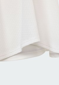 Biely texturovaný materiál s medovým vzorom, s hladkou vnútornou podšívkou a mierne zakriveným lemom. Detaily zahŕňajú prešitý okraj.