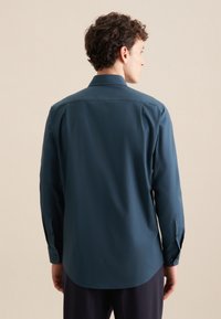Donkergroene lange mouwen shirt van gladde stof; heeft een standaard kraag en knoopmanchetten; achterkant toont een gebogen zoom.