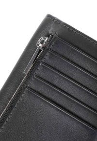 Esquina de billetera de cuero negro con superficie texturizada, múltiples ranuras para tarjetas y cierre de cremallera plateado para almacenamiento seguro.