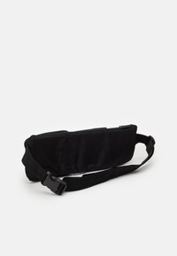 Černá látková ledvinka s hladkou texturou, obsahující zipové uzavření, nastavitelné ramenní popruhy a pevnou plastovou sponu. Minimalistický design.