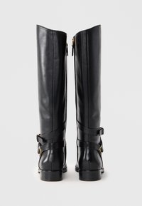 Black leather high-heeled boots with a straight shaft, featuring gold-toned hardware and a wrapped strap detail around the ankle.