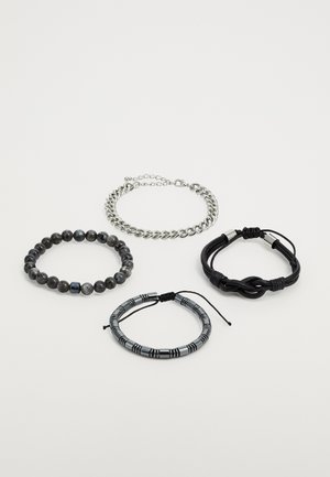 Štyri náramky: korálkový čierny náramok, strieborný reťaz, čierny kožený uzlový náramok a prúžkovaná kovová dekoratívna páska.