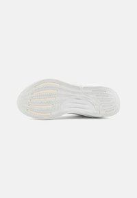 Suela de zapato deportivo blanca, que presenta goma texturizada con ranuras de flexión y un agarre con patrón. Secciones suaves en un tono más claro acentúan el diseño.