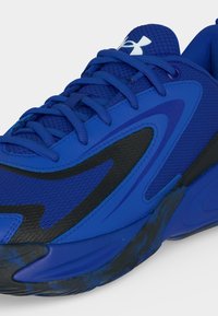 Gros plan d'une chaussure de sport bleue avec des accents noirs, tige en mesh, lacets bleus et semelle rembourrée.