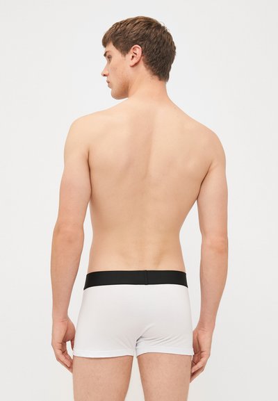 Weiße Boxershorts mit einem schwarzen Bund, aus glattem Stoff mit enger Passform, von hinten gezeigt.