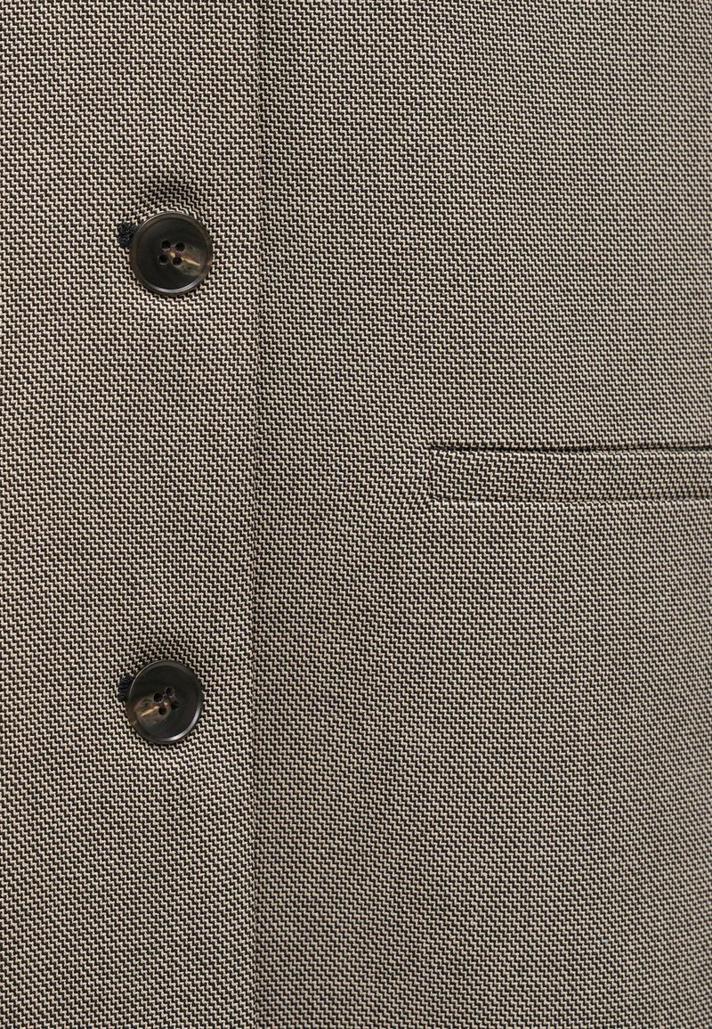 Getextureerde stof in een gedempte beige en zwarte visgraatstructuur, met twee zwarte knopen en een enkele paspelzak.