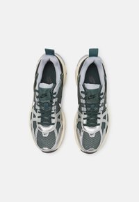 Nike-sneakers med ett överdel av grön mesh, silverdetaljer, rund tå, platta snören och en dämpad sula. Inkluderar en tab på hälen.