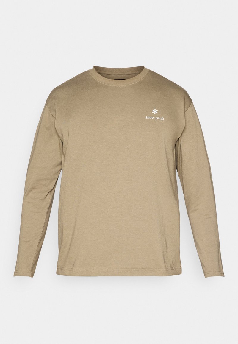 T-shirt beige à manches longues en tissu doux, avec un col rond et un petit logo blanc sur le côté gauche de la poitrine.