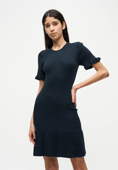 Πλεκτό φόρεμα με ριμπ ύφανση σε σκούρο μπλε ναυτικό χρώμα. Διαθέτει κοντά μανίκια με βολάν και φαρδιά τελείωμα. Φόρεμα με εφαρμοστή γραμμή και λεία υφή.