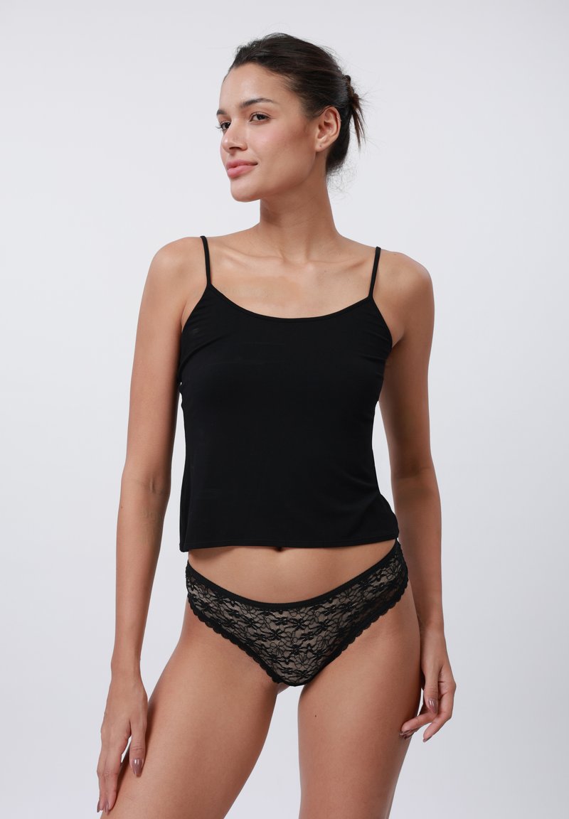 Svart camiset med tynne stropper, laget av glatt stoff; kombinert med svarte lace truser med blomstermønster og scalloped kanter.