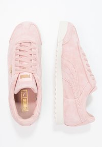 PUMA semišové tenisky v světle růžové barvě s tónovanými tkaničkami a zlatým logem na jazyku. Bílá gumová podrážka s texturovanými detaily.