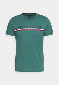 Camiseta de algodón verde con cuello redondo, mangas cortas y un audaz logotipo "HILFIGER" con franjas rojas, blancas y marinas en el pecho.