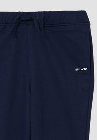 Marineblauwe joggingsbroek gemaakt van zachte stof, met een elastische tailleband met trekkoord en het witte 'SLVR' logo op het linkerbeen.