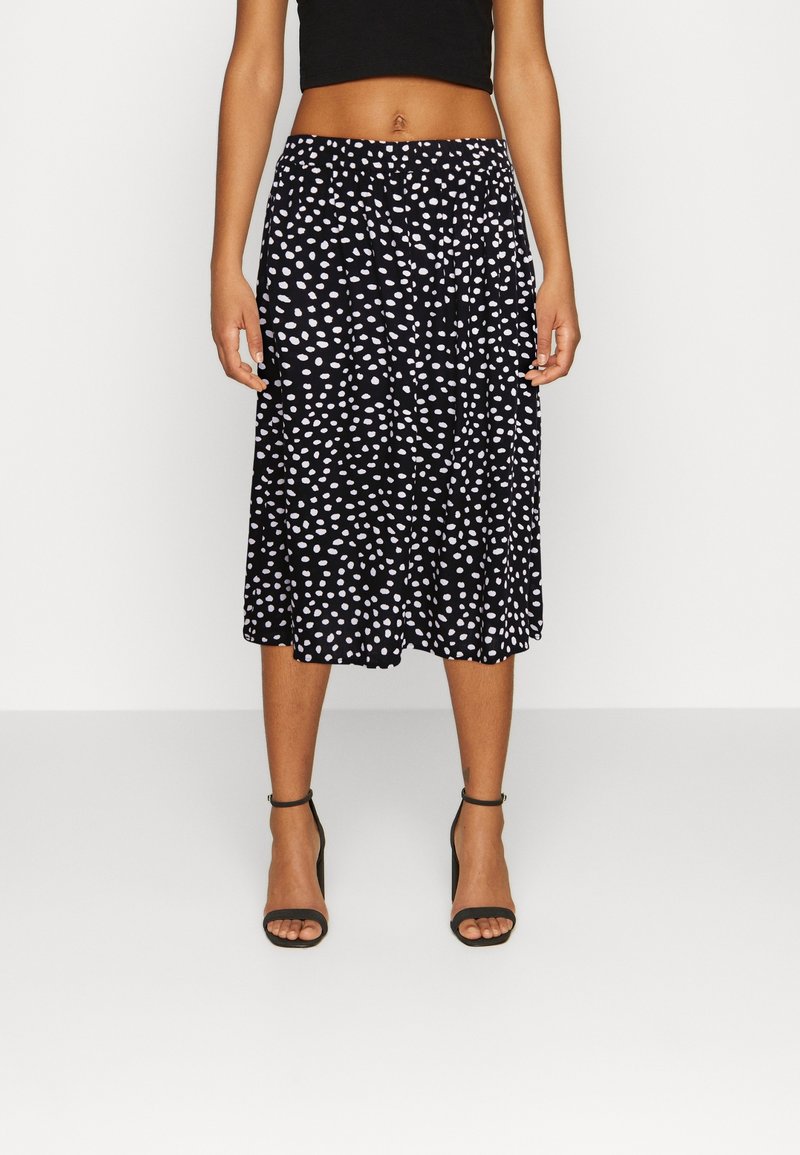 Jupe noire à pois blancs. Caractérisée par une coupe décontractée, une longueur genou, un tissu doux et une taille élastique.