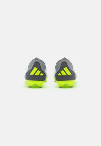 Chaussures de football athlétiques grises et noires avec des accents jaunes vifs, présentant un design épuré, un matériau texturé et des crampons moulés pour une meilleure traction.
