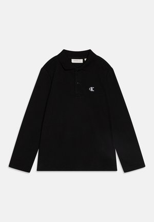Camisa polo preta de manga longa feita de algodão, com colarinho pontiagudo, aba de três botões e um logótipo bordado em branco no peito.