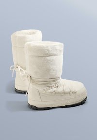 Hvide vandtætte støvler med en fluffy øvre skaft, sikret med snørebånd, der har en tekstureret gummisål for greb og holdbarhed.