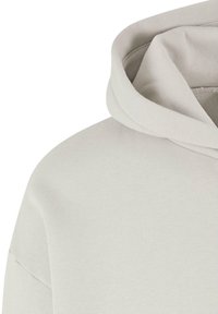 Light gray hoodie featuring a soft, textured fabric, large hood, and a relaxed fit design. Seam details are minimal and unobtrusive.
