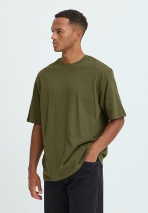 Olivenfarvet bomulds T-shirt med rund halsudskæring, korte ærmer og en afslappet pasform. Kombineret med sorte jeans for kontrast.