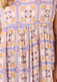 Robe en tissu léger à motifs géométriques avec des motifs solaires, des designs floraux et une taille plissée. Les couleurs incluent le rose pastel, le jaune et le bleu.