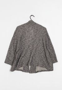 Gray speckled knit cardigan with long sleeves hanging on a black hanger against a white background.