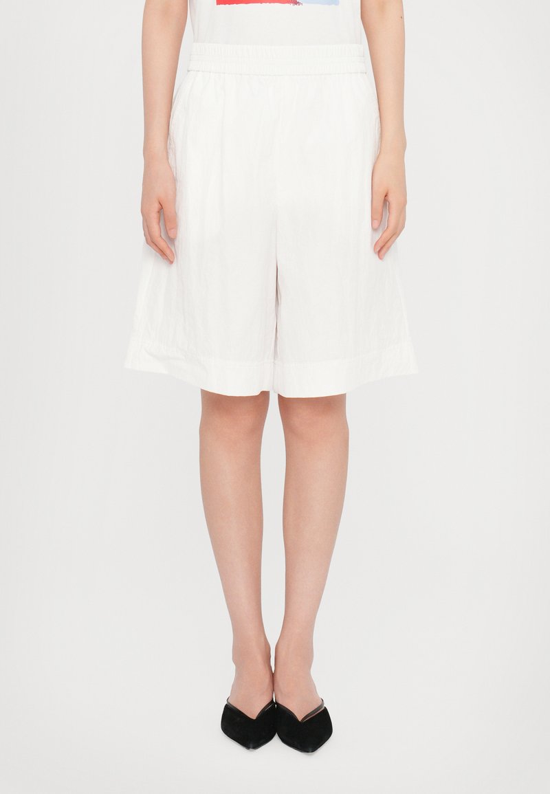 Hvite, knelange shorts laget av lett materiale med elastisk midje, som har en glatt tekstur og enkelt kantdesign.