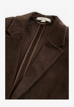 Brūns kordurojas žakete ar teksturētu rakstu, ar iegrieztiem atloki un slēptu rāvējslēdzēju. Iekšējais oderējums atbilstošā brūnā tonī.