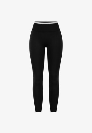 Zwarte naadloze leggings met een brede geribbelde tailleband en een slanke pasvorm, hoog in de taille, afgebeeld tegen een witte achtergrond.