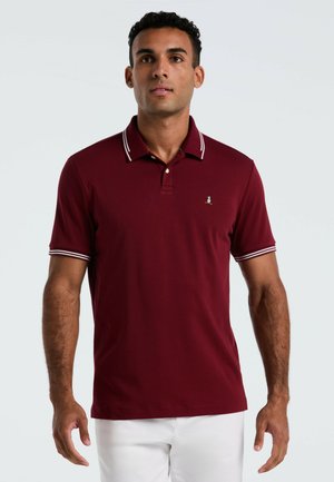 Bordeaux polo T-shirt met witte afwerking op de kraag en mouwen. Bevat een klein, geborduurd logo op de borst. Zachte, gladde textuur.