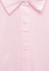 Svetloružová košeľa s button-down golierom, mierne štruktúrovanou látkou a vertikálnou légiou s gombíkmi.