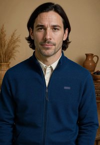 Marine blauwe ritstrui met gestructureerde horizontale strepen op de borst, zachte stof en een opstaande kraag. Voorzien van een klein logo-detail.