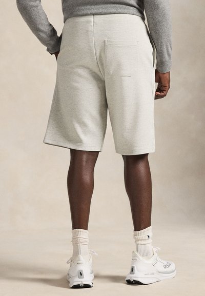 Light gray, knee-length shorts made from soft fabric, featuring a back pocket and side slits, paired with white athletic shoes and socks.