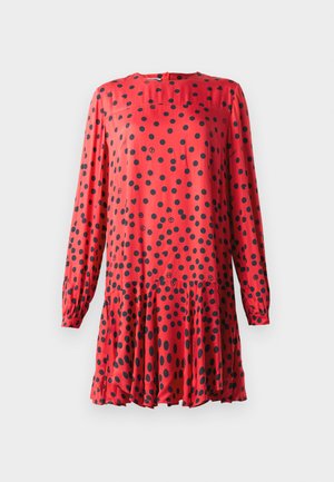 Robe rouge à manches longues, avec un col rond et des pois noirs. Ourlet évasé avec une taille froncée pour un aspect fluide.