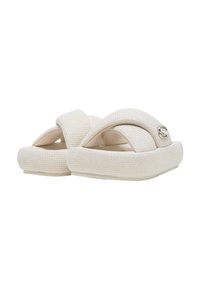 Paire de sandales blanches à plateforme avec des brides en tissu texturé et un petit emblème métallique sur une bride.
